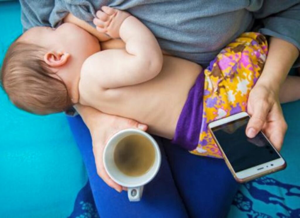 Mother drinking coffee while breastfeeding